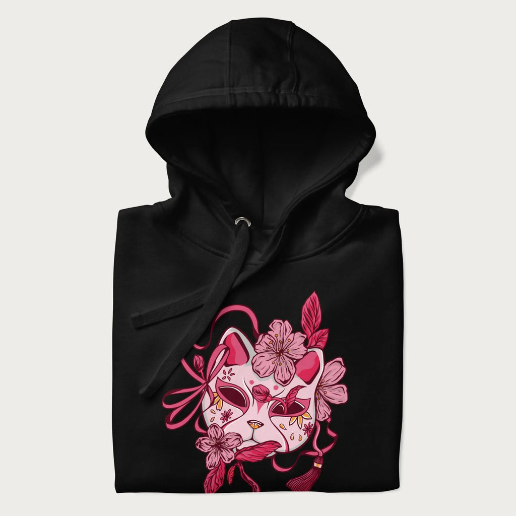 Folded black hoodie with a Japanese kitsune mask and sakura design on the front.
