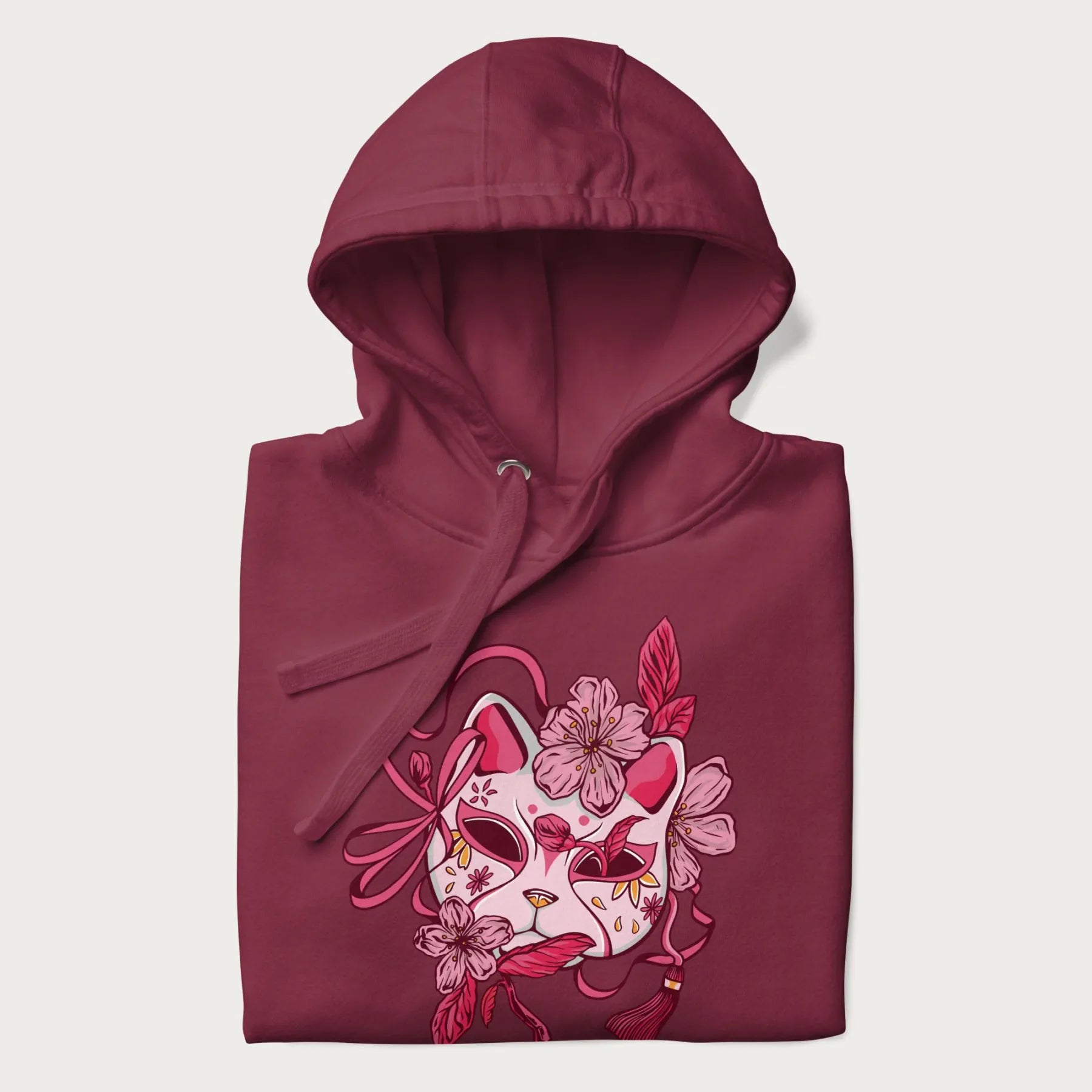 Folded maroon hoodie with a Japanese kitsune mask and sakura design on the front.