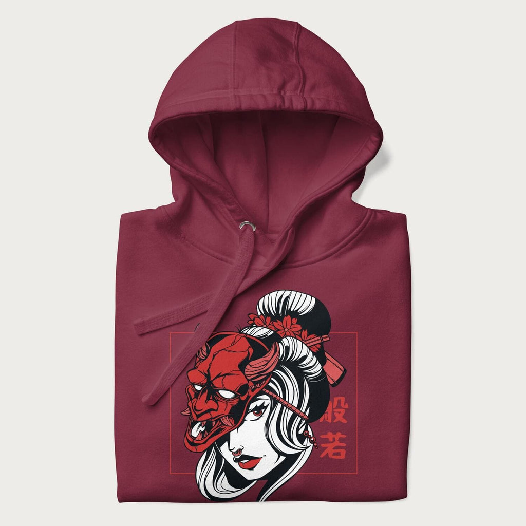 Neatly folded Japanese hoodie in a maroon colorway with a graphic of a geisha wearing a hannya mask.