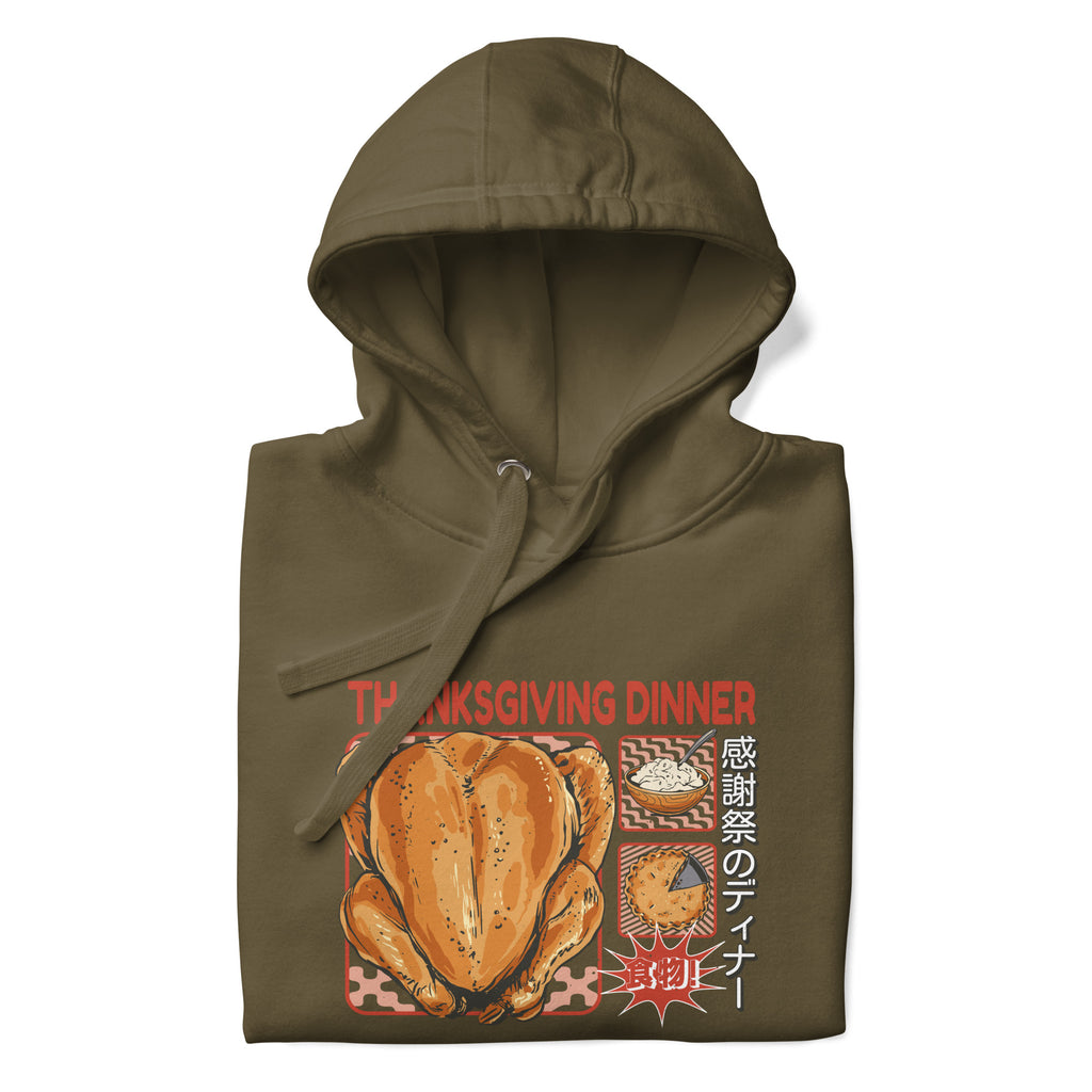 Folded Japanese Thanksgiving Hoodie in Military Green color: An earthy military green hoodie featuring a graphic depicting a Japanese Thanksgiving feast, including a roast chicken, Japanese potato salad, and an apple pie. The hoodie is neatly folded.