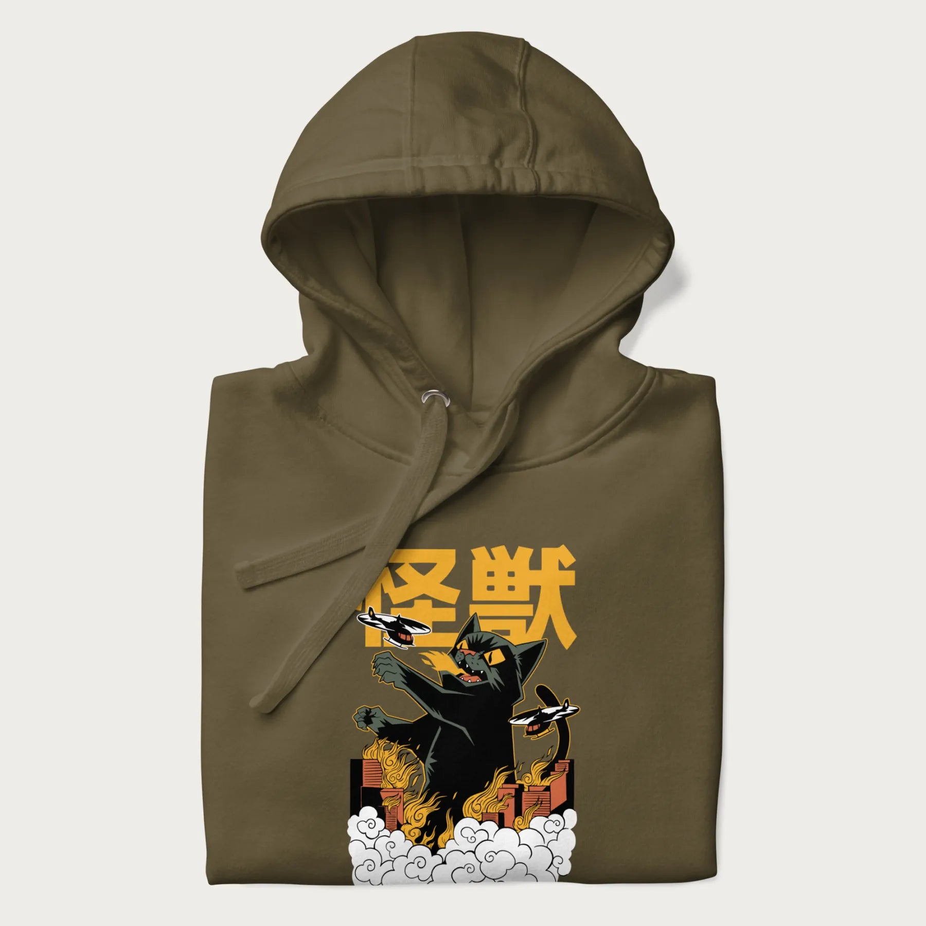 Folded military green hoodie with graphic of a 'Kaiju Cat' with helicopters and flames in a burning city.