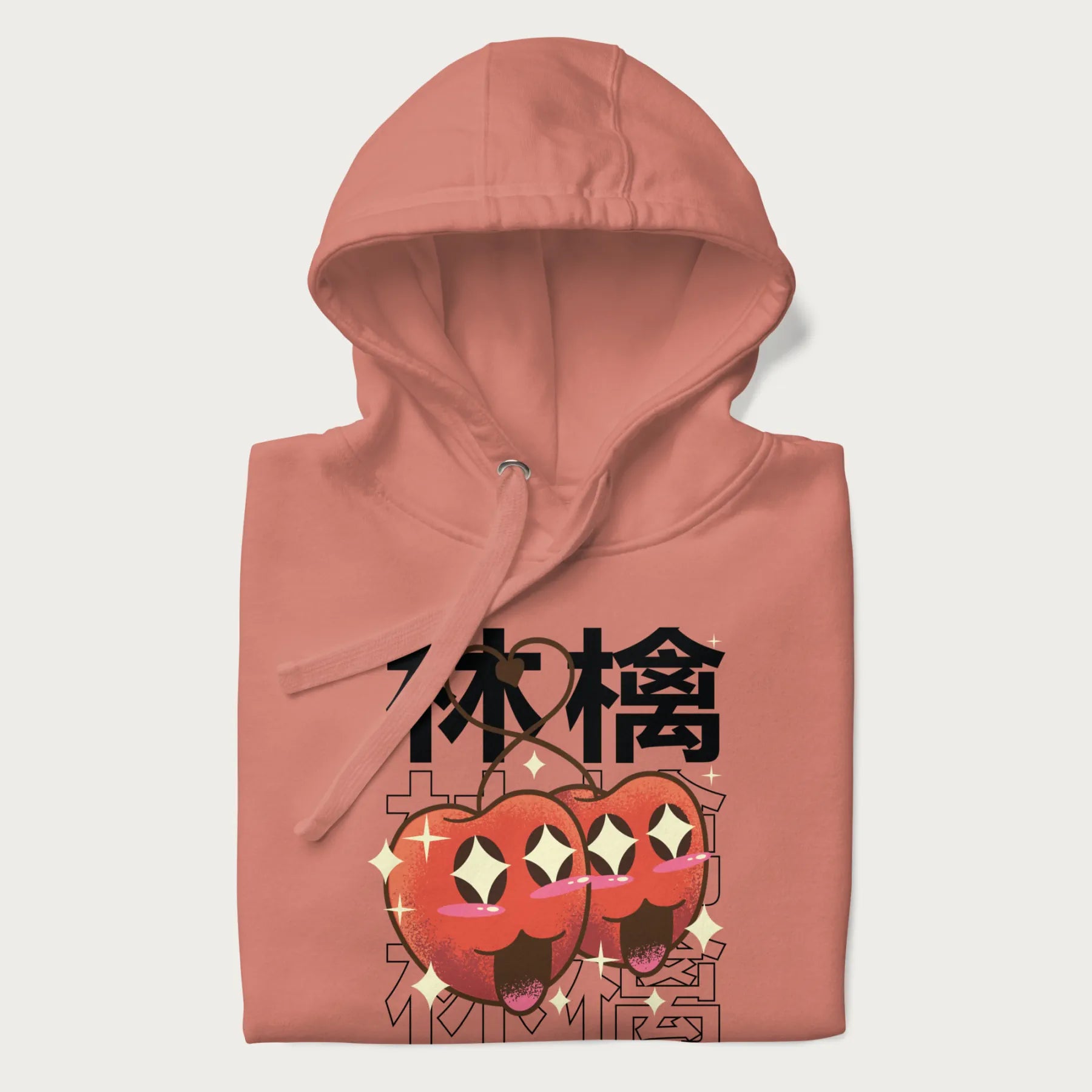 Folded light pink hoodie with Japanese graphic of two cute apples with kawaii faces, surrounded by the Japanese text '林檎' (Apple)