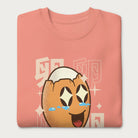 Folded light pink sweatshirt with Japanese text and a kawaii boiled egg graphic with sparkling eyes..