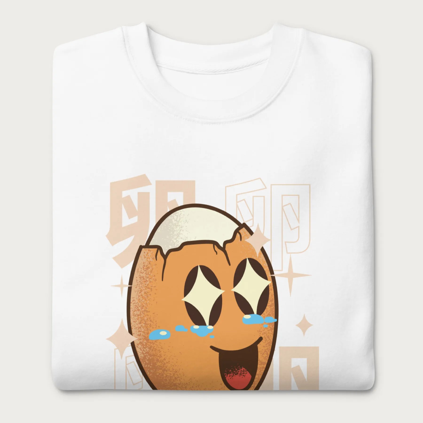 Folded white sweatshirt with Japanese text and a kawaii boiled egg graphic with sparkling eyes..