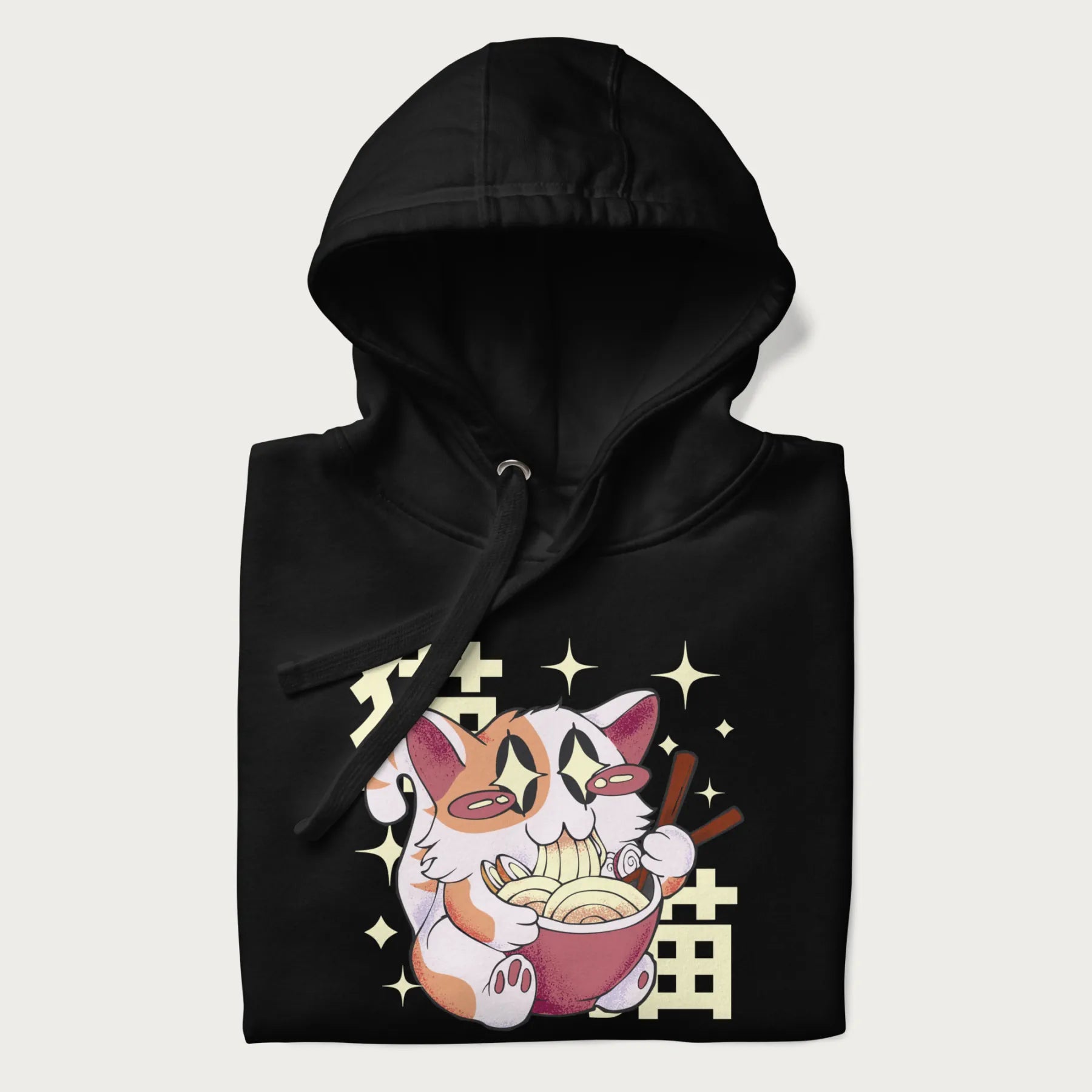 Folded black hoodie with Japanese graphic of a cat eating ramen with Japanese text '猫' in the background.