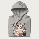 Folded light grey hoodie with Japanese graphic of a cat eating ramen with Japanese text '猫' in the background.