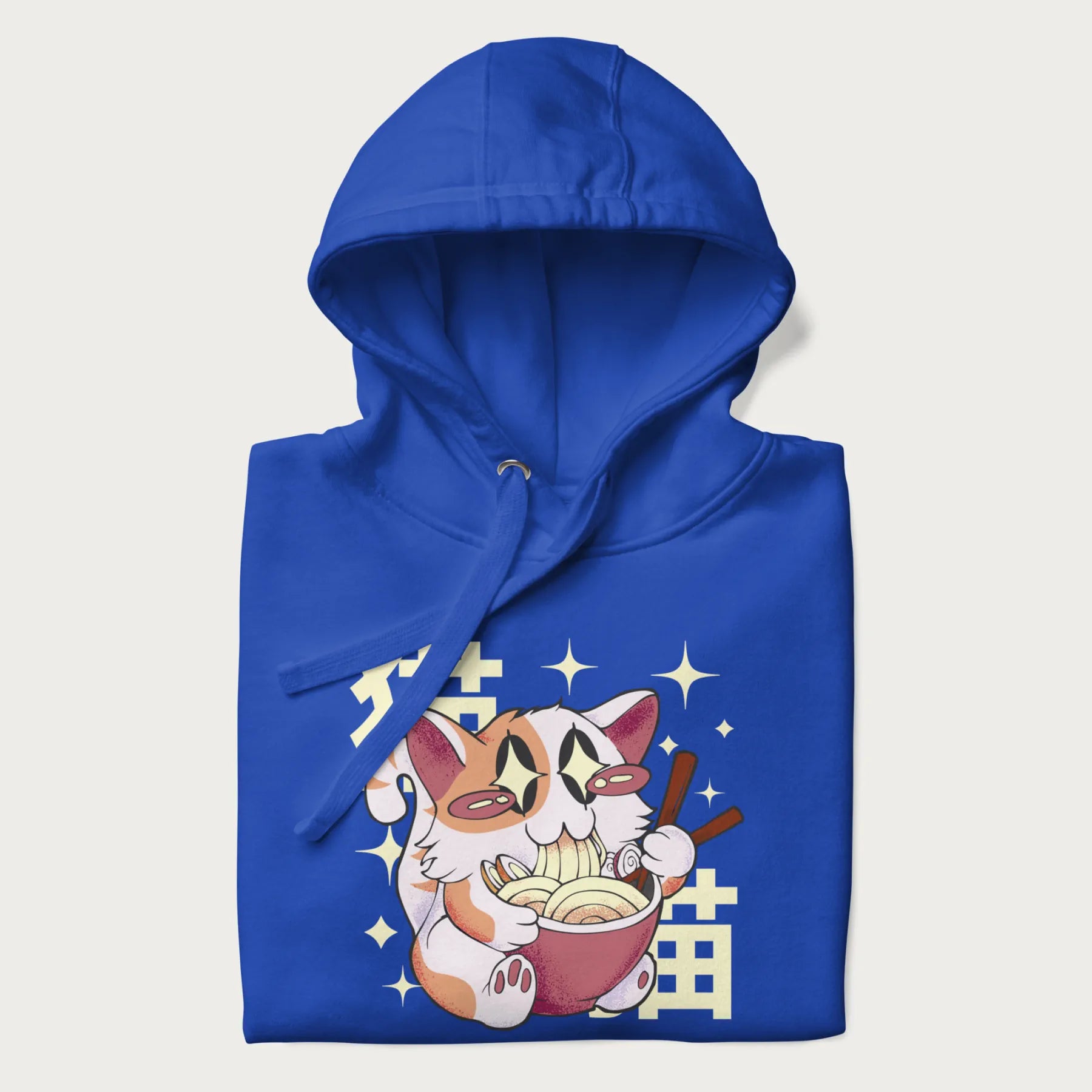 Folded royal blue hoodie with Japanese graphic of a cat eating ramen with Japanese text '猫' in the background.