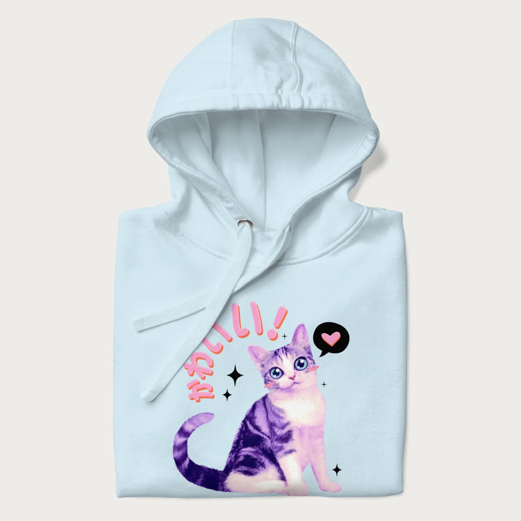 Folded light blue hoodie with a graphic of a blue-eyed kitten and Japanese kawaii-style lettering, stars, and a heart.