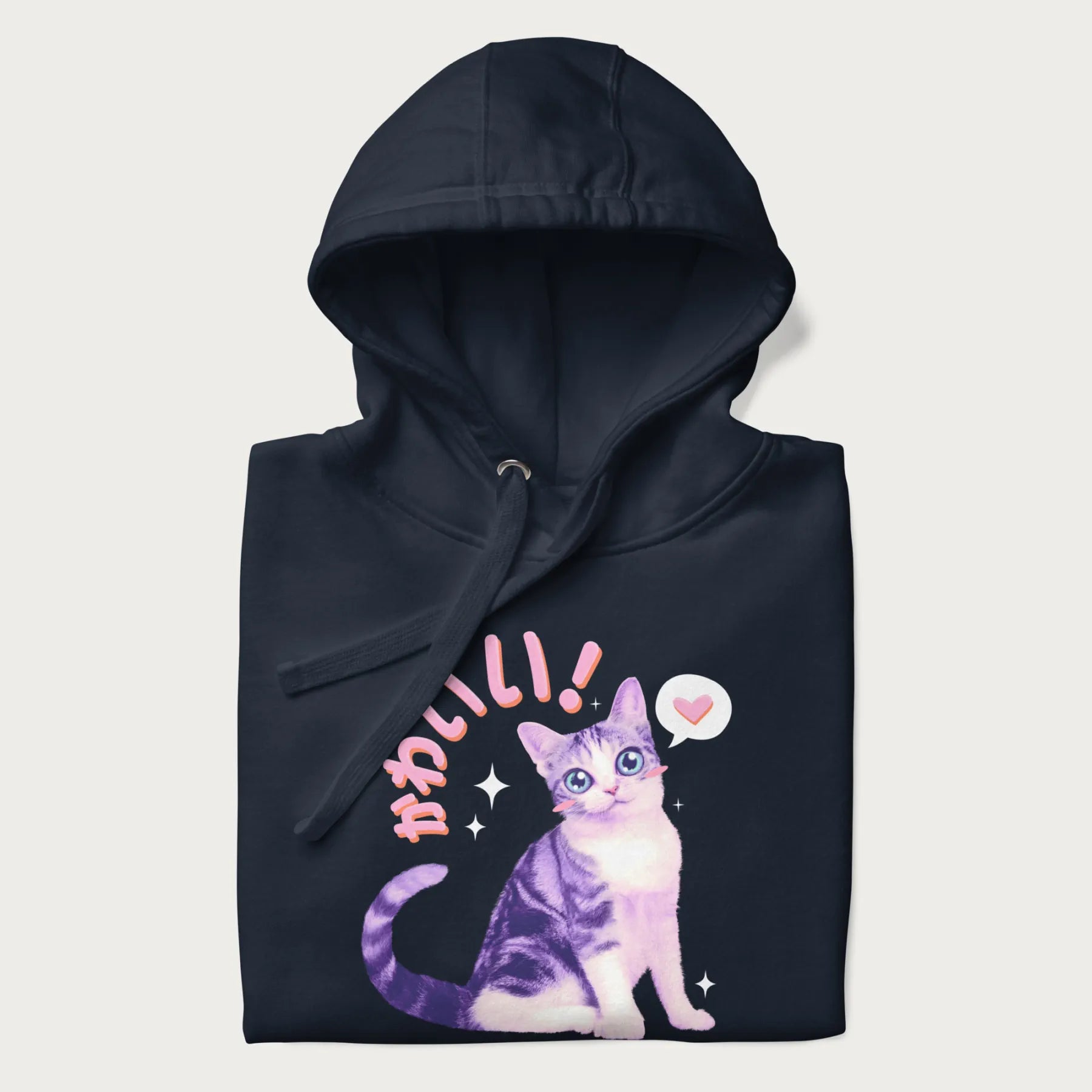 Folded navy blue hoodie with a graphic of a blue-eyed kitten and Japanese kawaii-style lettering, stars, and a heart.