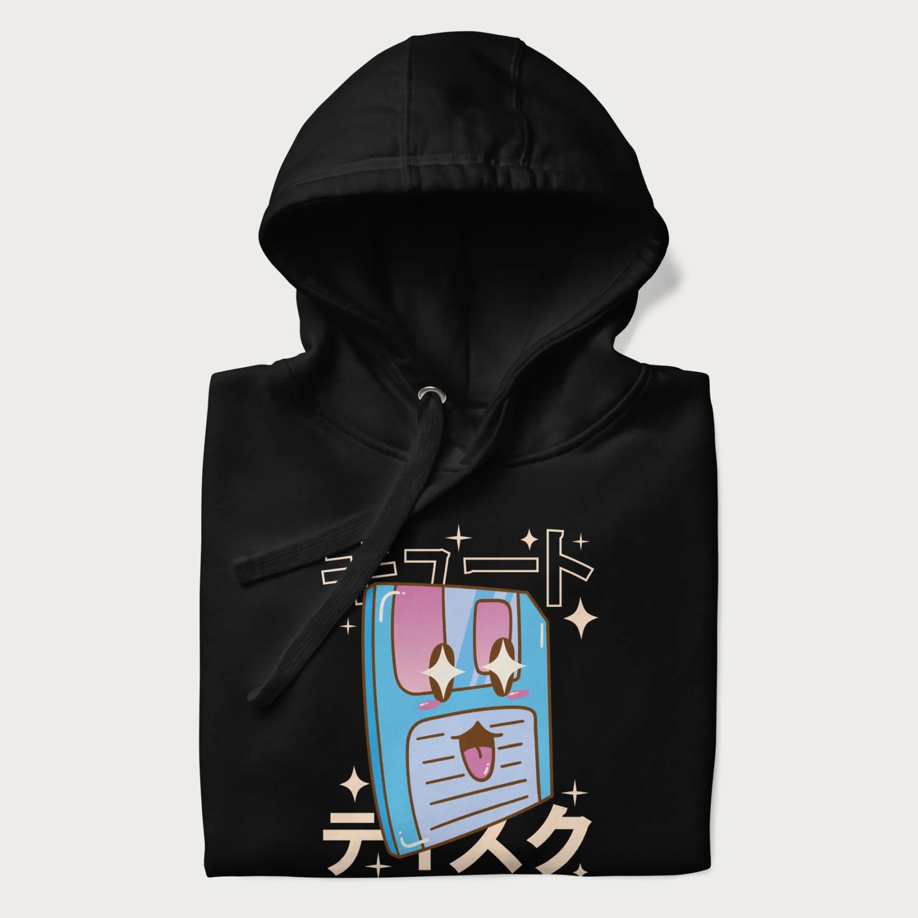 Folded black hoodie with Japanese graphic of a cute sky-blue floppy disk with Japanese text 'キュート' (Cute) and 'ティスク' (Disk).