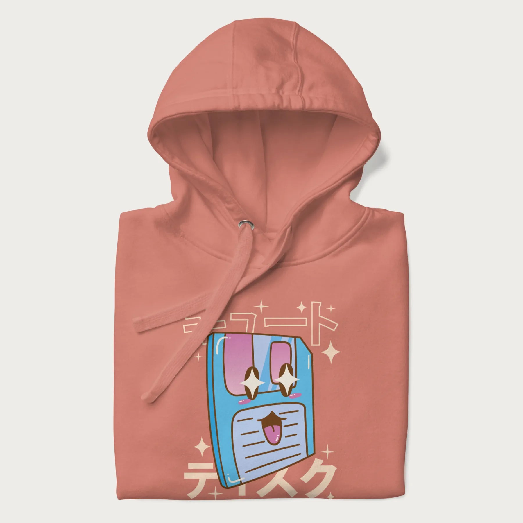 Folded light pink hoodie with Japanese graphic of a cute sky-blue floppy disk with Japanese text 'キュート' (Cute) and 'ティスク' (Disk).