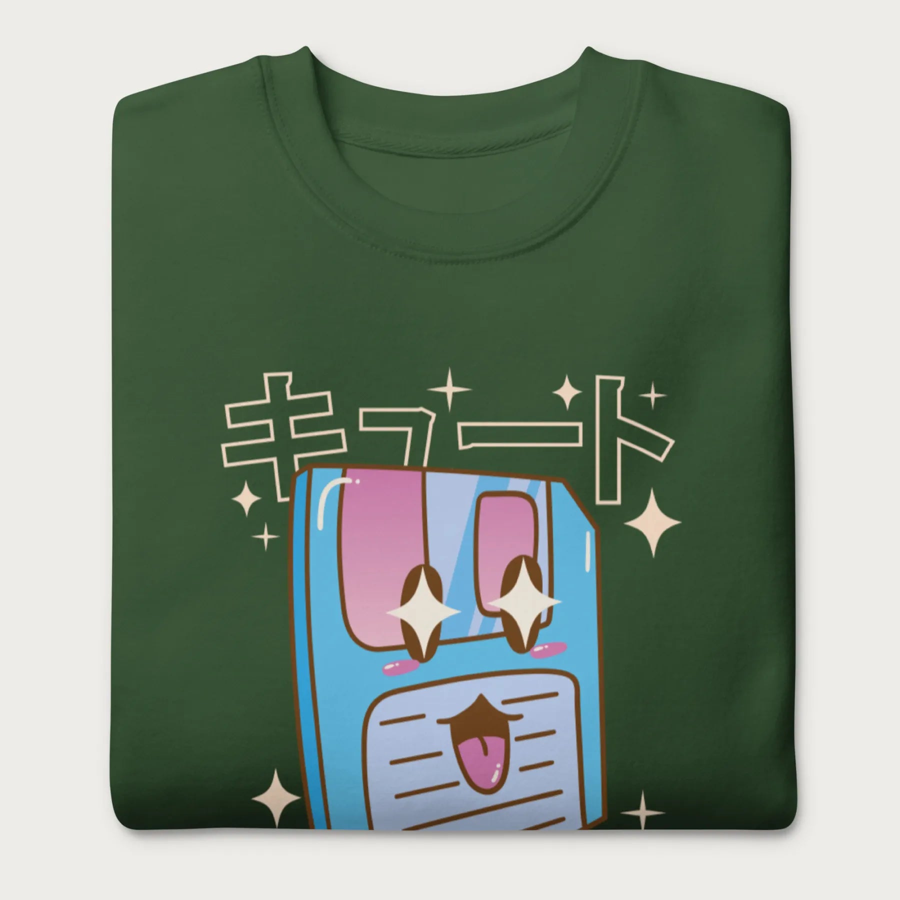 Folded forest green sweatshirt with a kawaii floppy disk graphic in vibrant colors and Japanese text.