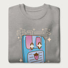 Folded light grey sweatshirt with a kawaii floppy disk graphic in vibrant colors and Japanese text.