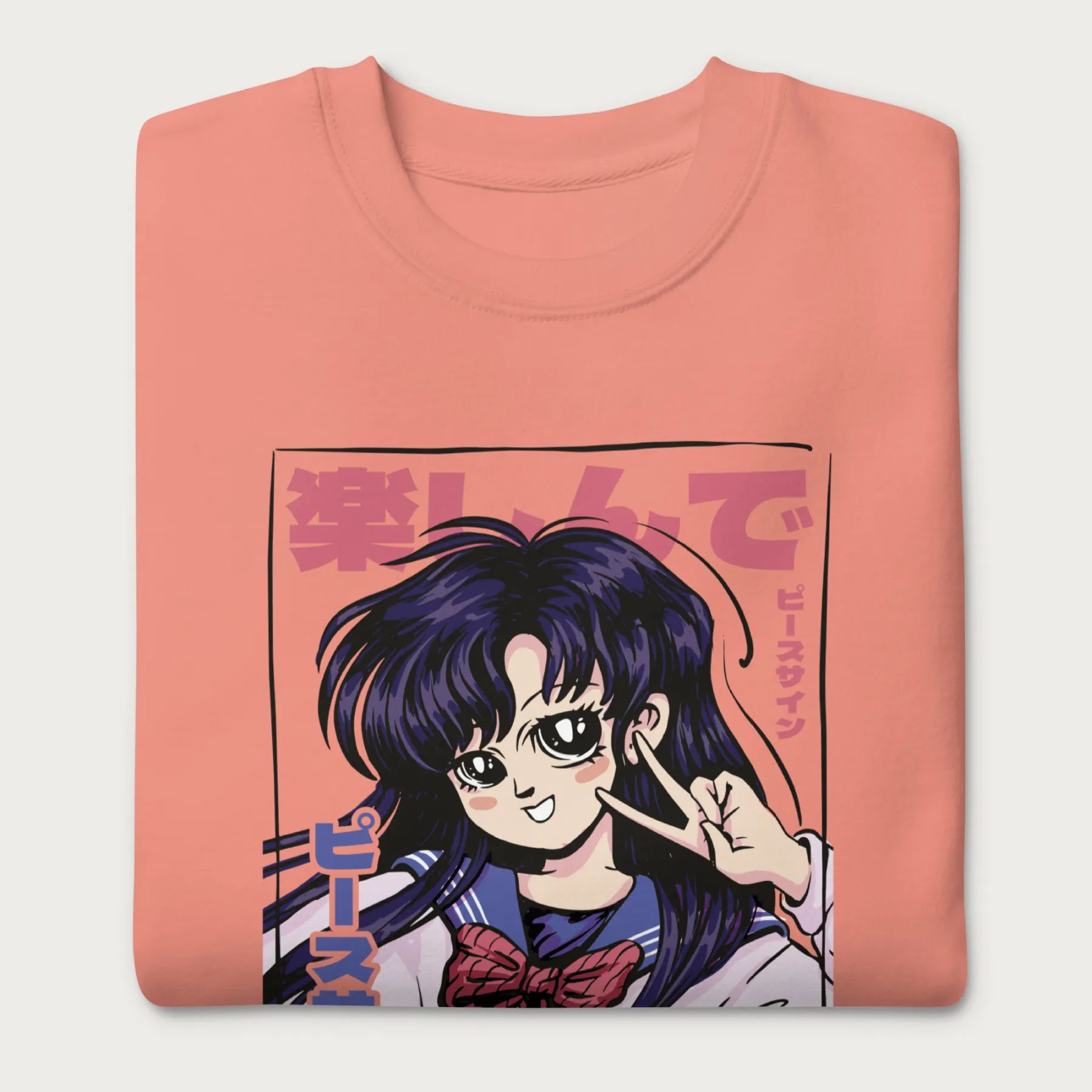 Folded light pink sweatshirt with a vibrant graphic of an anime girl flashing a peace sign with bold Japanese text.