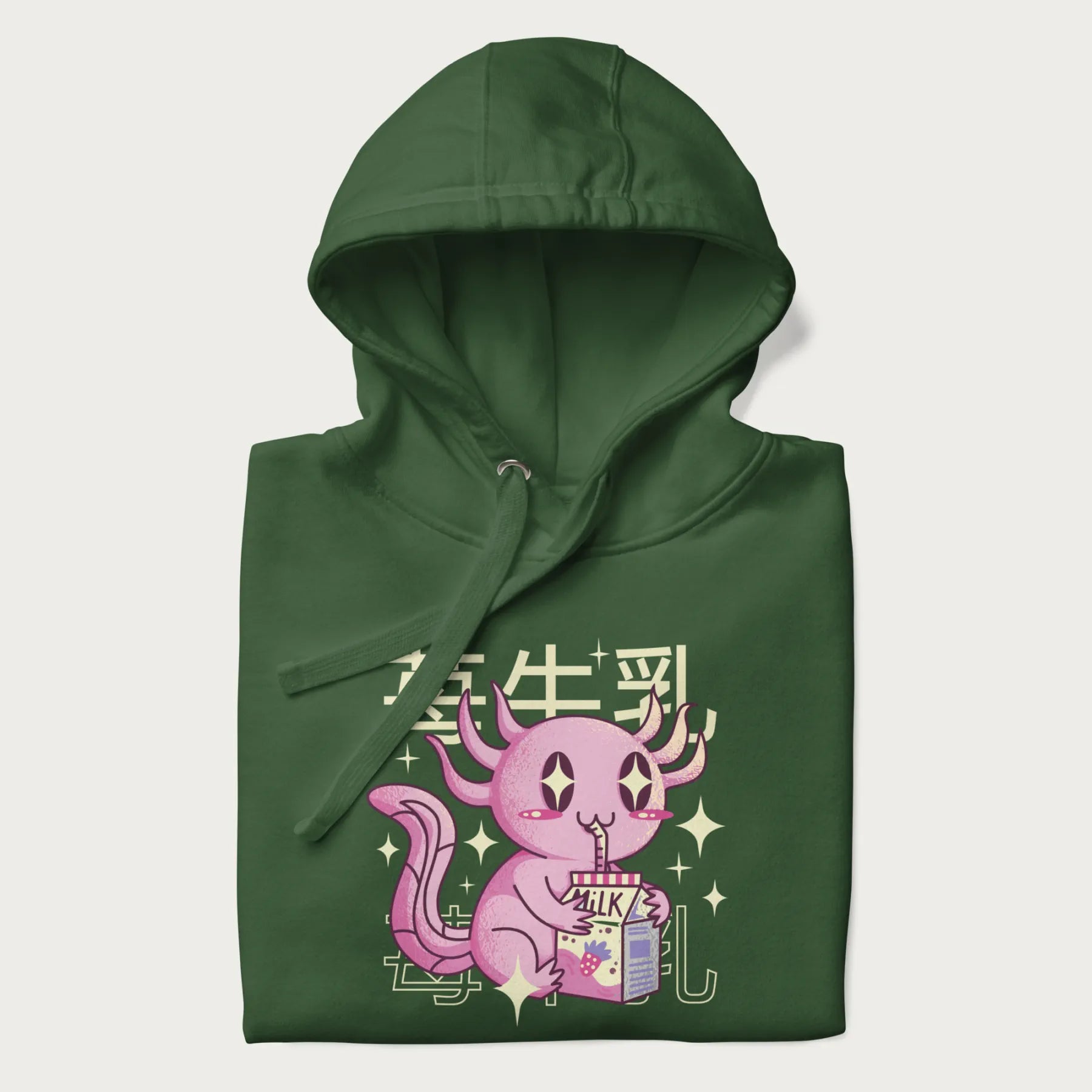 Folded forest green hoodie with Japanese graphic of a cute pink axolotl sipping strawberry milk from a carton, with Japanese text '苺牛乳' (Strawberry Milk).