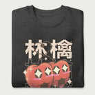 Folded dark grey sweatshirt with Japanese text and a kawaii red apple graphic.