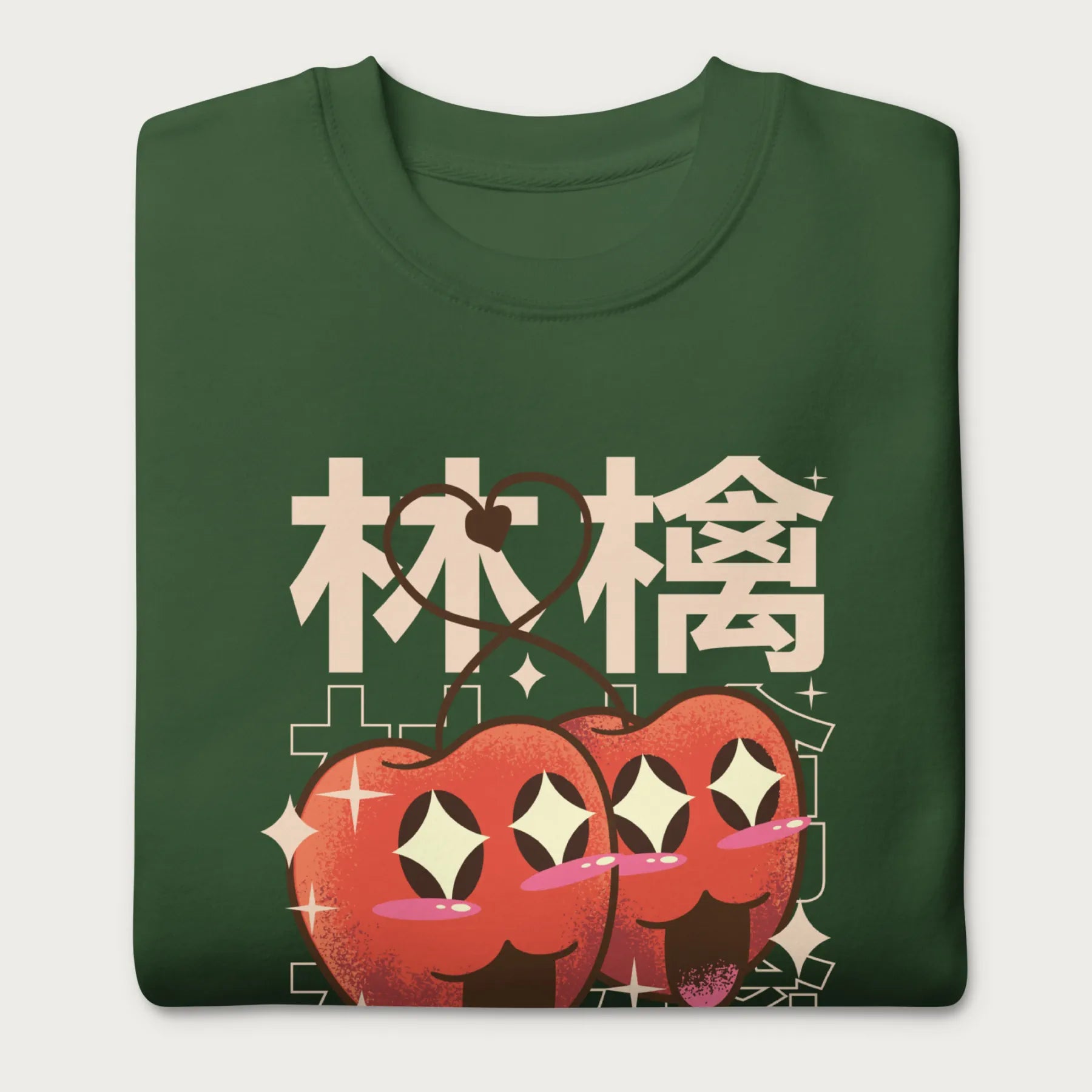 Folded forest green sweatshirt with Japanese text and a kawaii red apple graphic.