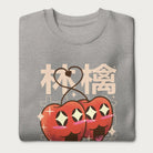 Folded light grey sweatshirt with Japanese text and a kawaii red apple graphic.