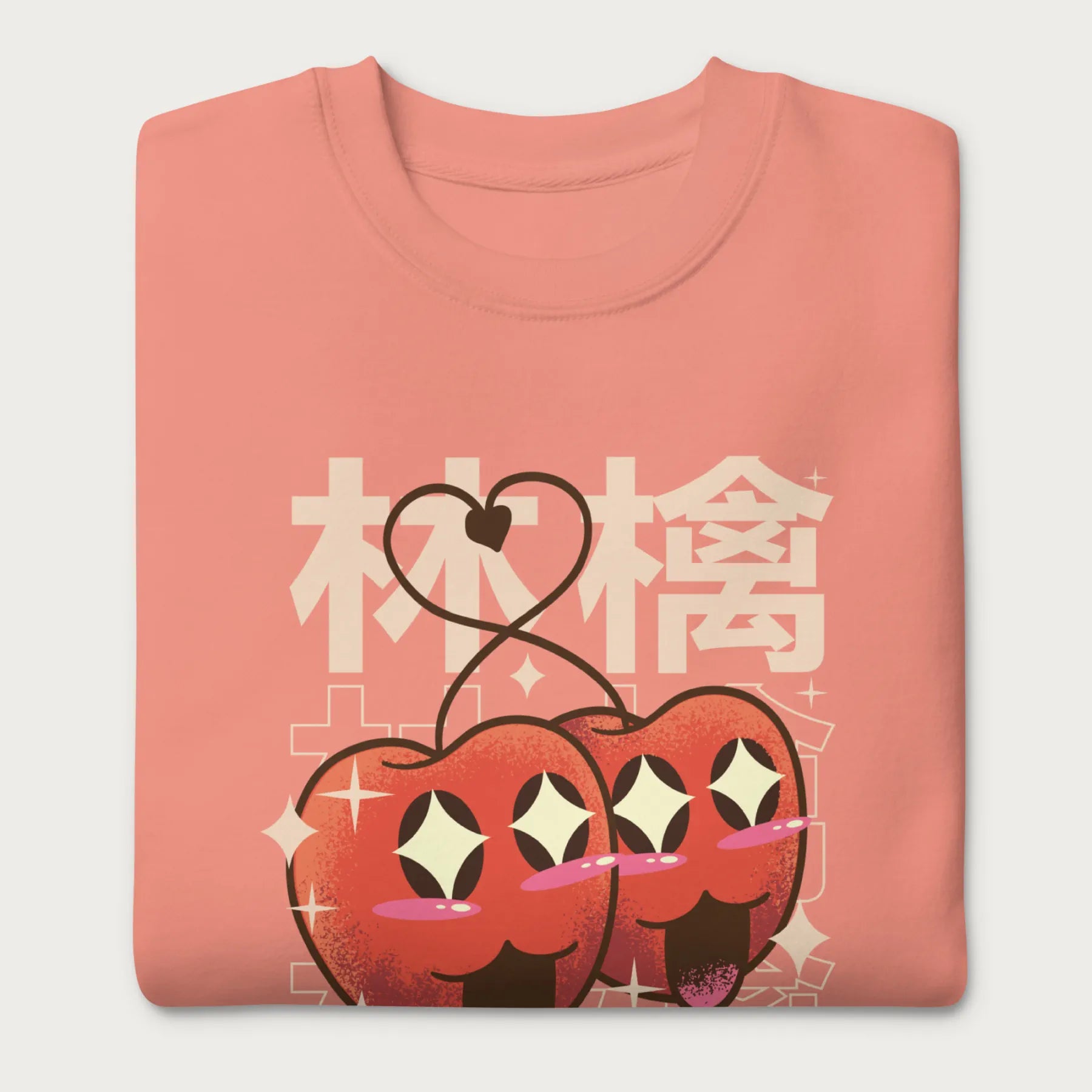 Folded light pink sweatshirt with Japanese text and a kawaii red apple graphic.