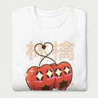 Folded white sweatshirt with Japanese text and a kawaii red apple graphic.