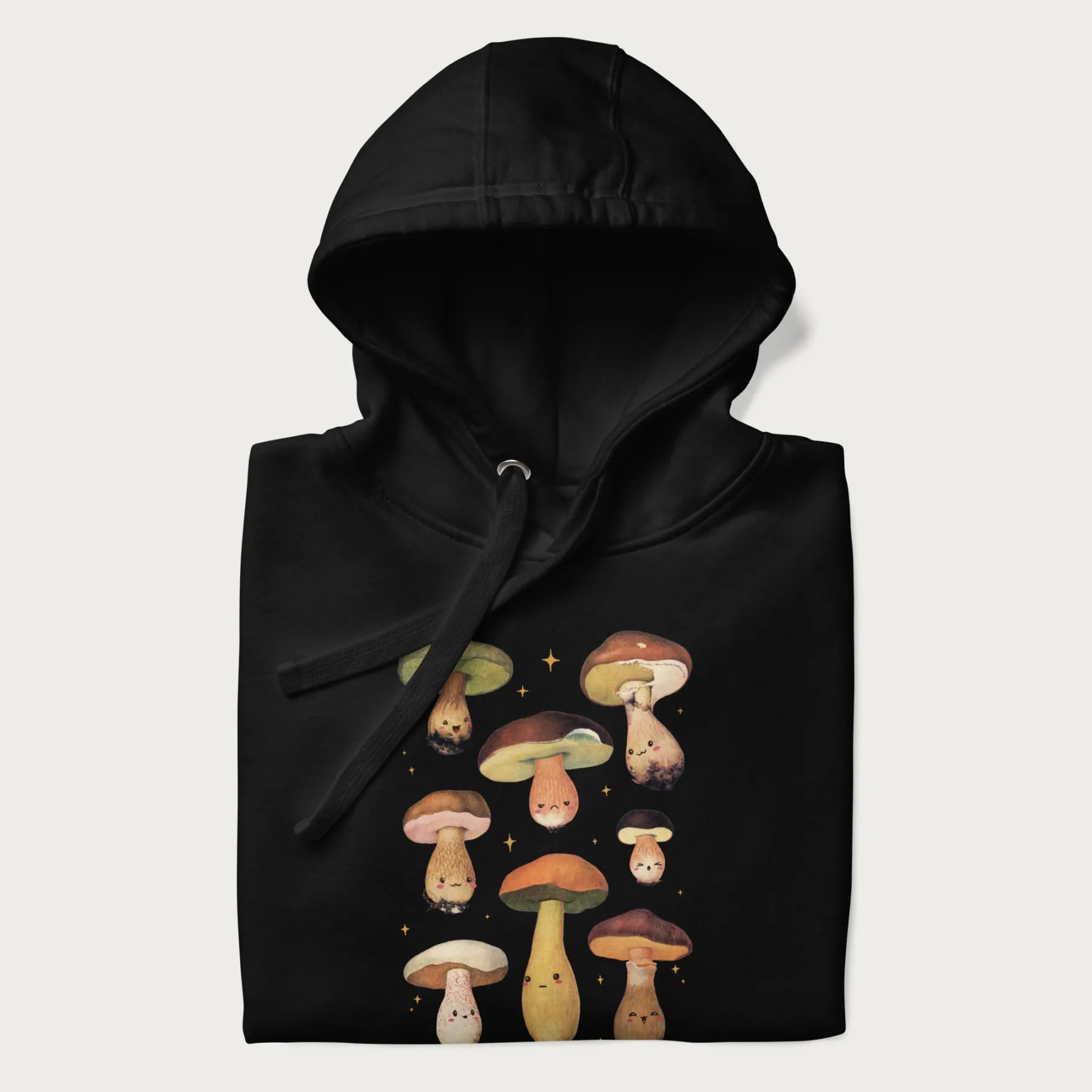 Folded black hoodie with Japanese graphic of cute and expressive mushrooms with various faces.