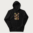 Black hoodie with Japanese graphic of cute and expressive mushrooms with various faces.