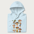 Folded light blue hoodie with Japanese graphic of cute and expressive mushrooms with various faces.