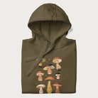 Folded military green hoodie with Japanese graphic of cute and expressive mushrooms with various faces.