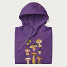 Folded purple hoodie with Japanese graphic of cute and expressive mushrooms with various faces.