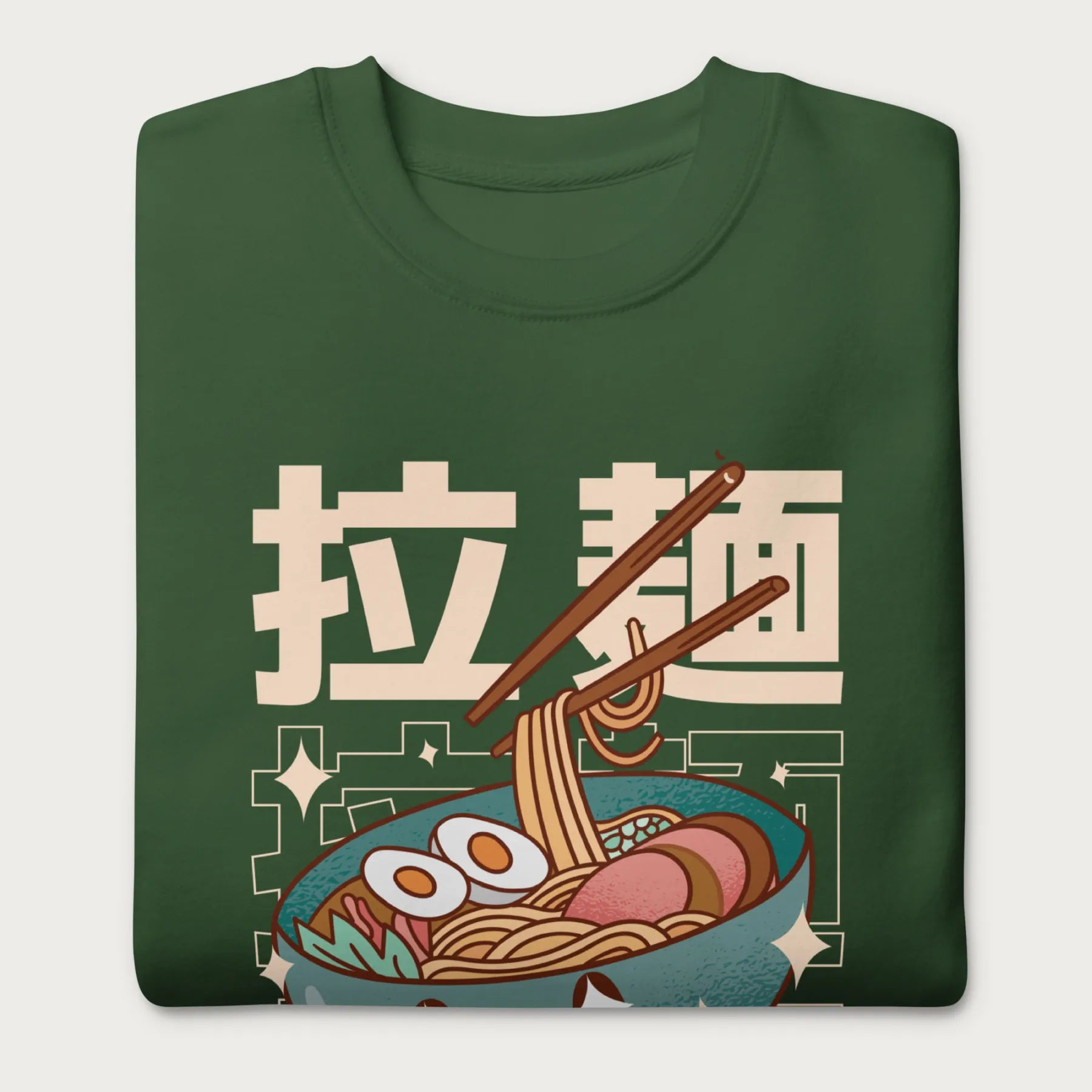 Folded forest green sweatshirt with Japanese text and a kawaii ramen bowl graphic.