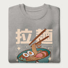 Folded light grey sweatshirt with Japanese text and a kawaii ramen bowl graphic.