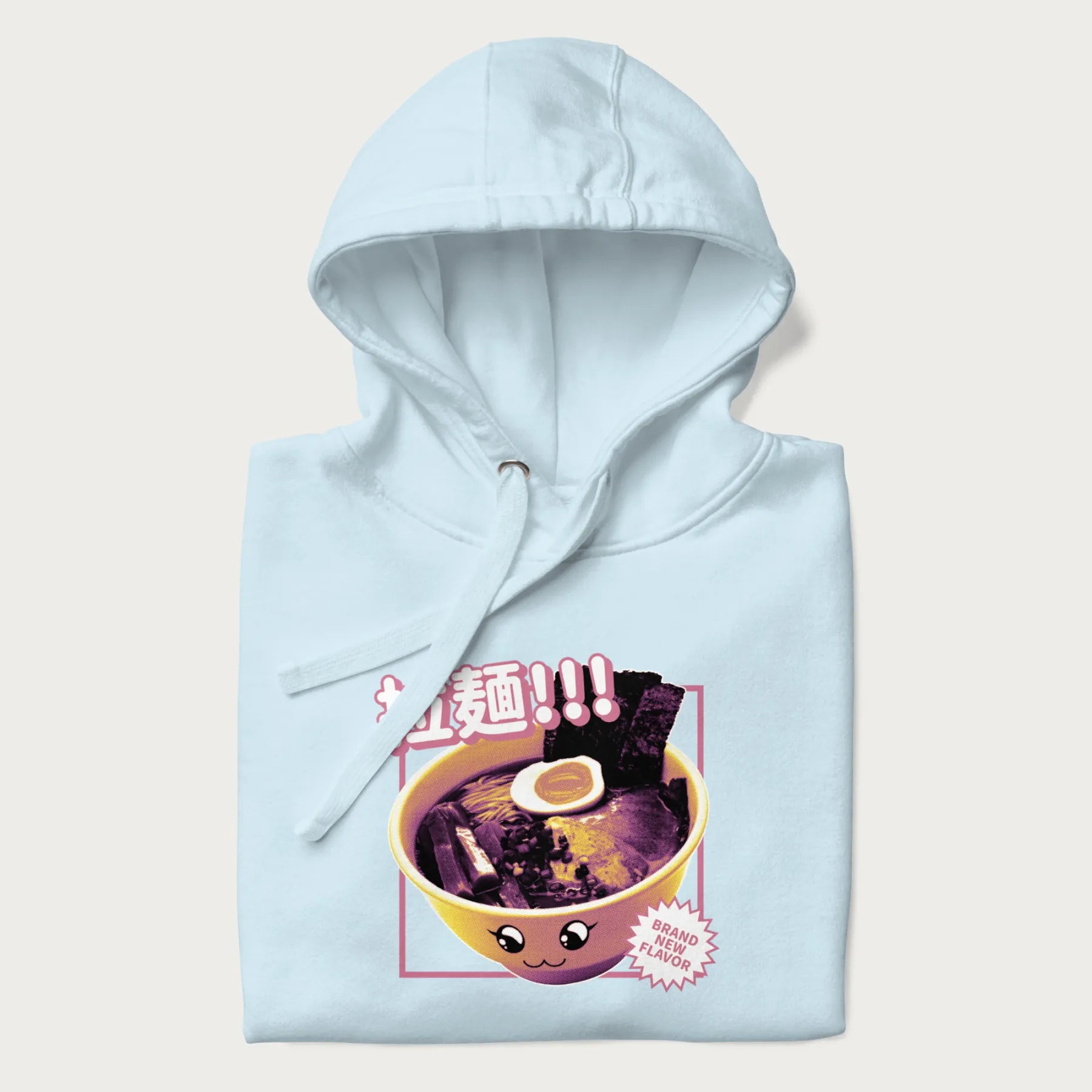 Folded light blue hoodie with Japanese text '拉麵!!!' (Ramen!!!) in vibrant pink and realistic ramen bowl graphic.