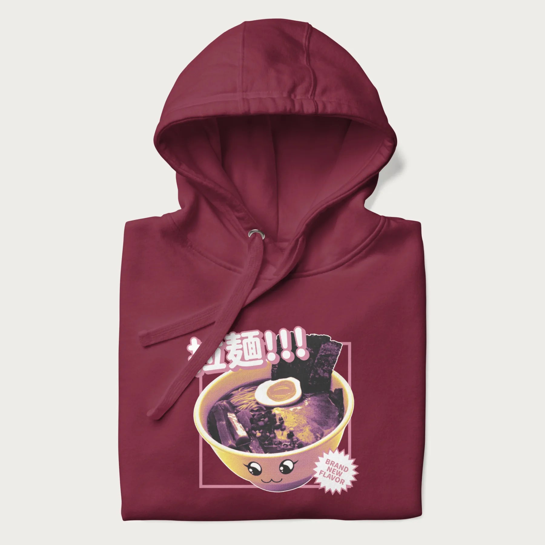 Folded maroon hoodie with Japanese text '拉麵!!!' (Ramen!!!) in vibrant pink and realistic ramen bowl graphic.