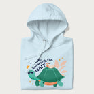 Folded light blue hoodie with graphic of a turtle and duck with sunglasses and the text 'Late but Worth the Wait'.