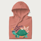 Folded light pink hoodie with graphic of a turtle and duck with sunglasses and the text 'Late but Worth the Wait'.