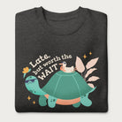 Folded dark grey sweatshirt with a graphic of a turtle and bird wearing sunglasses with the phrase 'Late But Worth the Wait.'