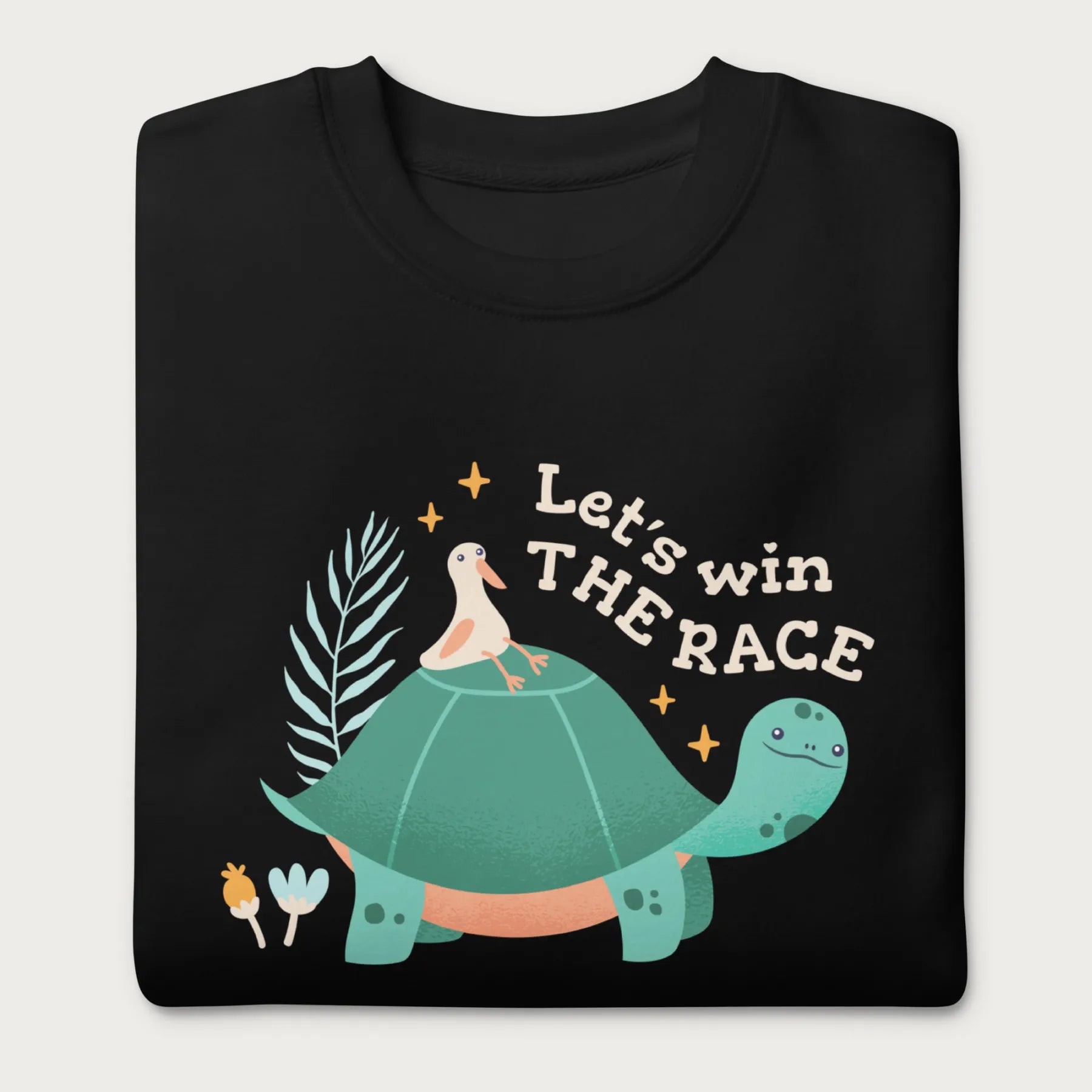 Folded black sweatshirt with a graphic of a turtle with a bird on it's shell with the phrase 'Let's Win the Race.'