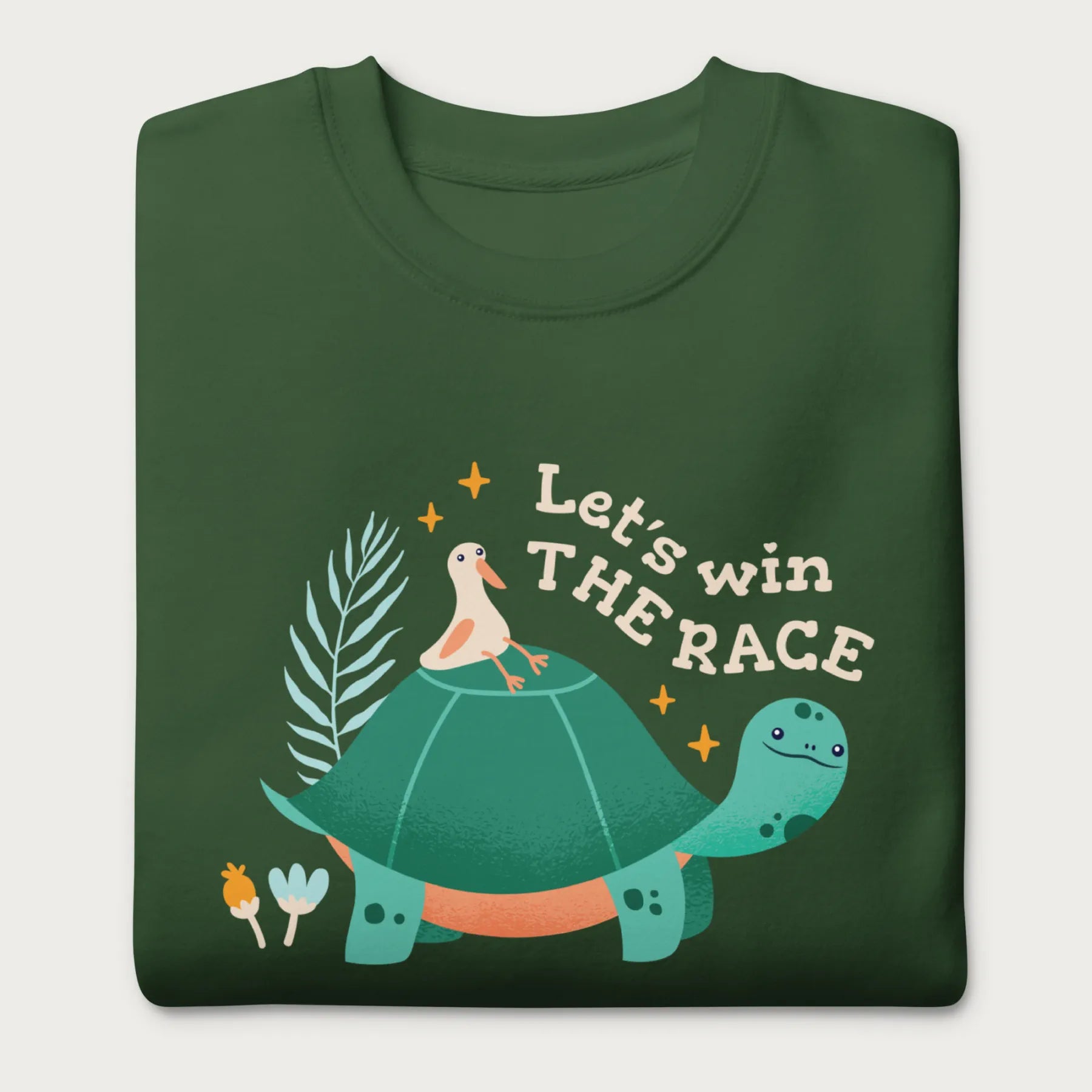 Folded forest green sweatshirt with a graphic of a turtle with a bird on it's shell with the phrase 'Let's Win the Race.'