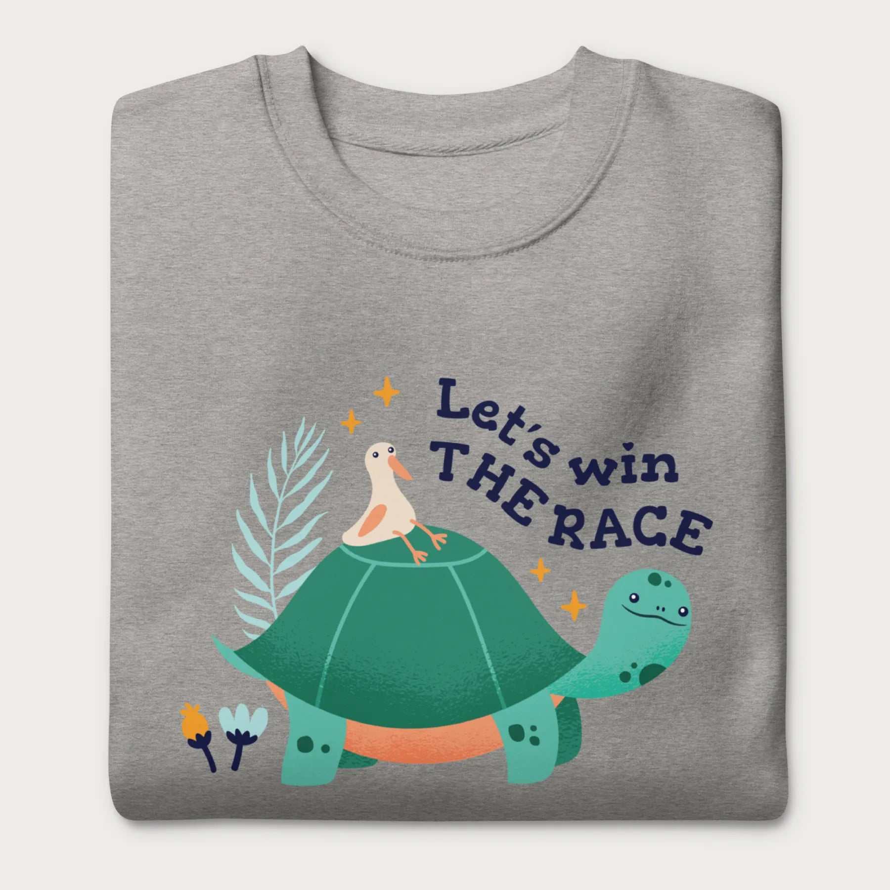 Folded light grey sweatshirt with a graphic of a turtle with a bird on it's shell with the phrase 'Let's Win the Race.'