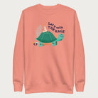 Light pink sweatshirt with a graphic of a turtle with a bird on it's shell with the phrase 'Let's Win the Race.'