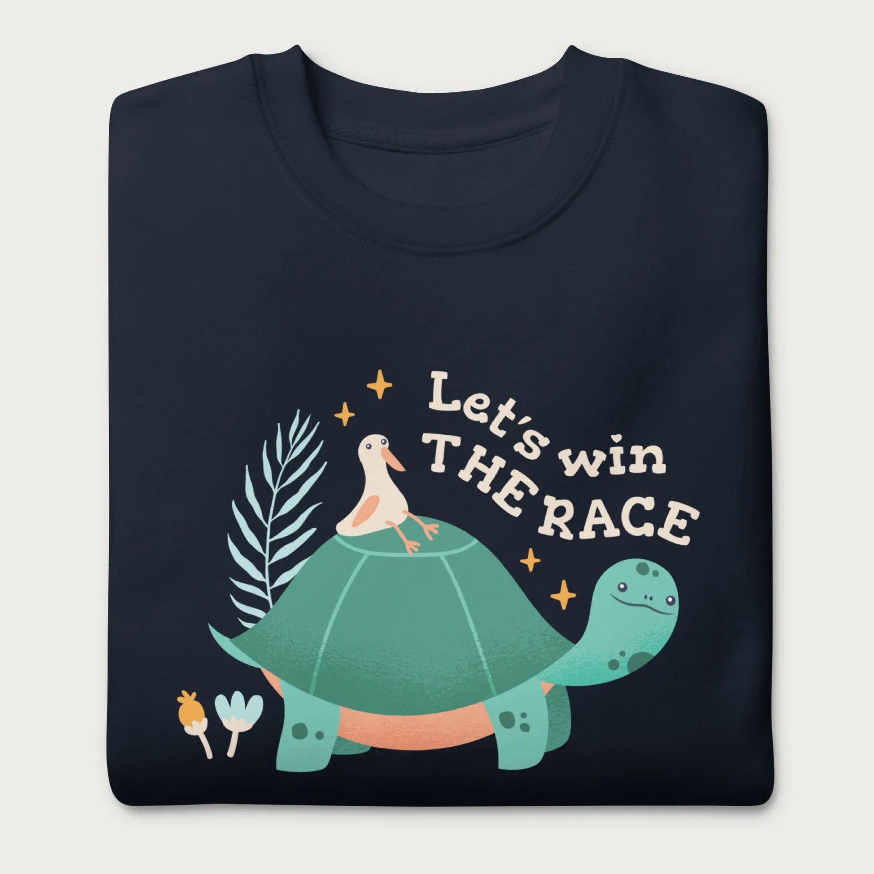 Folded navy blue sweatshirt with a graphic of a turtle with a bird on it's shell with the phrase 'Let's Win the Race.'