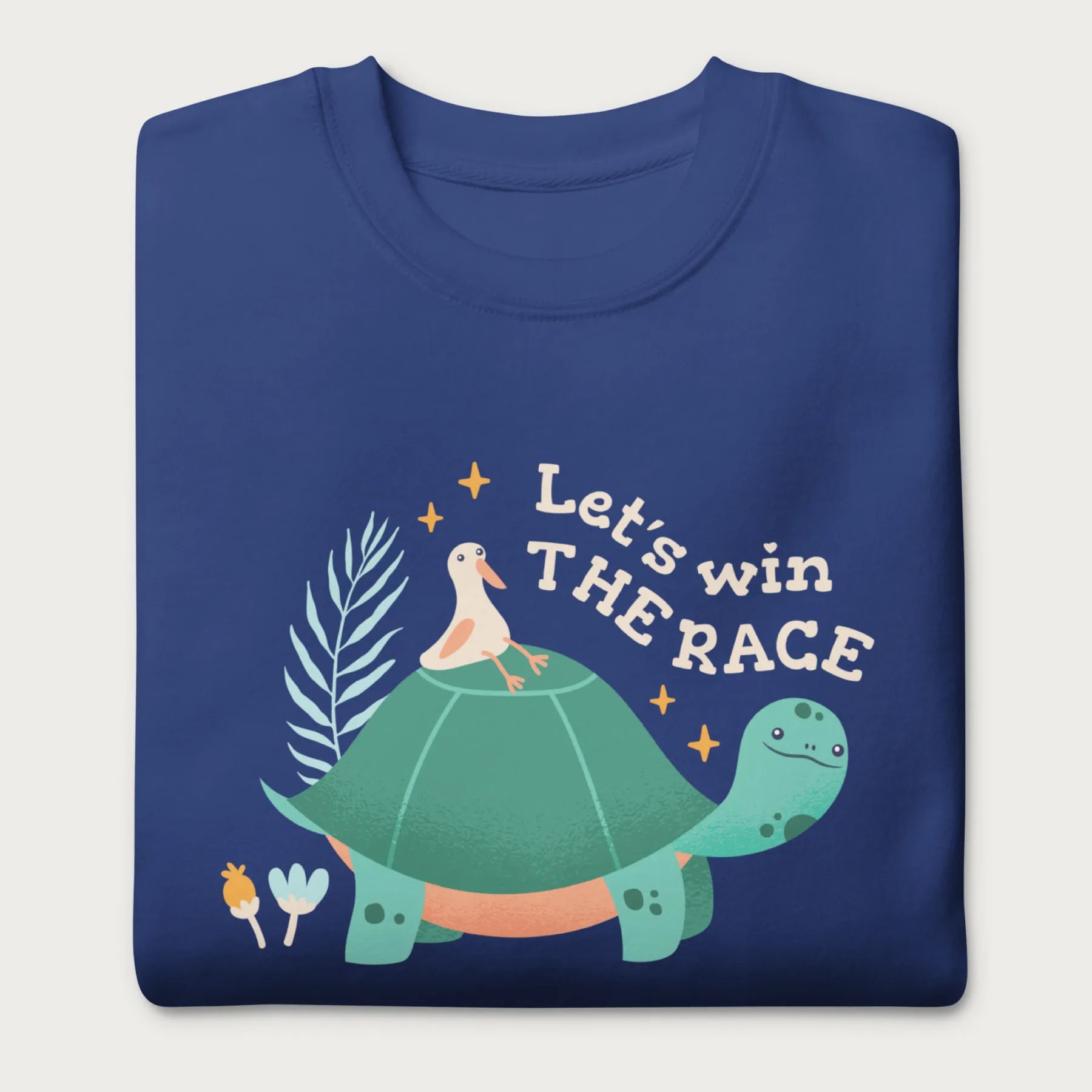 Folded royal blue sweatshirt with a graphic of a turtle with a bird on it's shell with the phrase 'Let's Win the Race.'