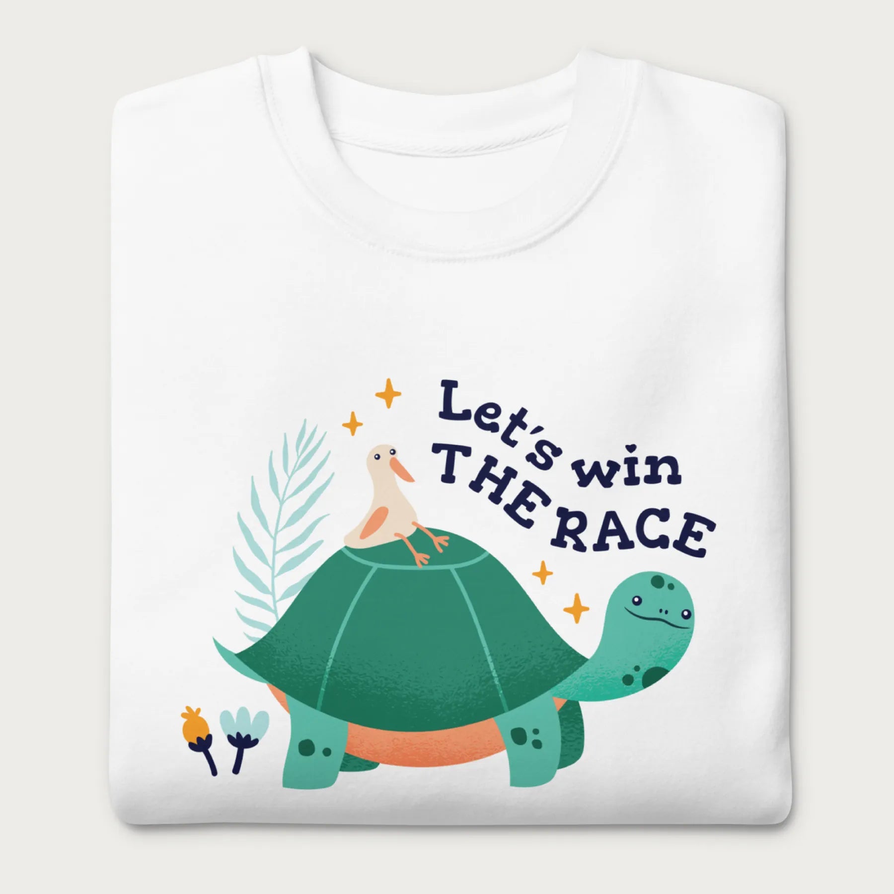 Folded white sweatshirt with a graphic of a turtle with a bird on it's shell with the phrase 'Let's Win the Race.'