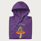 Folded purple hoodie with graphic of a dapper frog reading a book on a mushroom with the text 'Don't Be Stressing, Life's a Blessing' above and below.