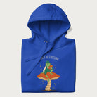 Folded royal blue hoodie with graphic of a dapper frog reading a book on a mushroom with the text 'Don't Be Stressing, Life's a Blessing' above and below.