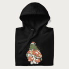 Folded black hoodie with graphic of a frog in a Santa hat on a mushroom with Christmas lights and the text 'Merry Christmas' below.