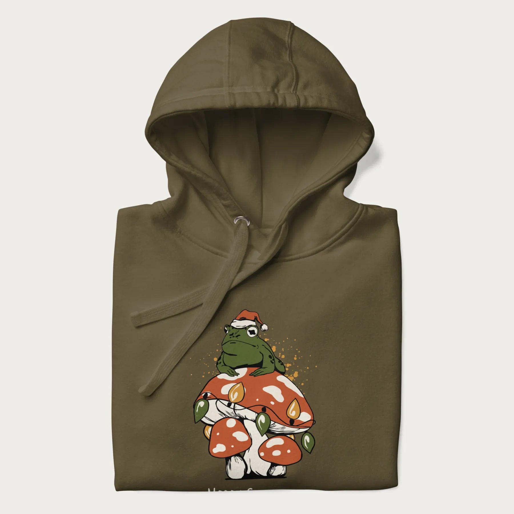 Folded military green hoodie with graphic of a frog in a Santa hat on a mushroom with Christmas lights and the text 'Merry Christmas' below.