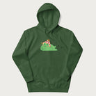 Forest green hoodie with a cottagecore design of a green frog wearing a mushroom cap and a snail on top.