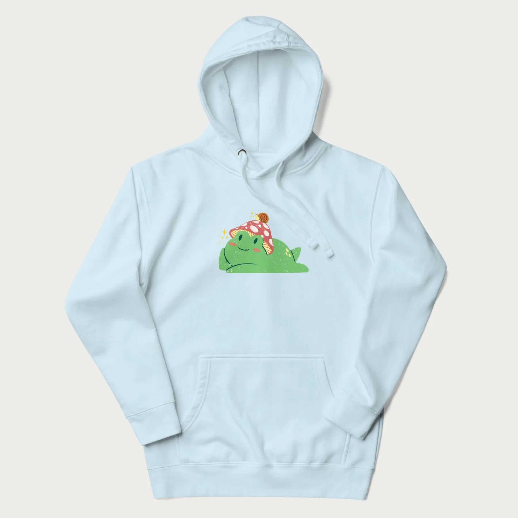 Light blue hoodie with a cottagecore design of a green frog wearing a mushroom cap and a snail on top.