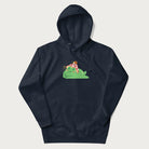 Navy blue hoodie with a cottagecore design of a green frog wearing a mushroom cap and a snail on top.